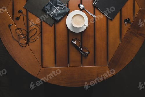 Preview: top view of coffee cup, eyeglasses and notepads on wooden table