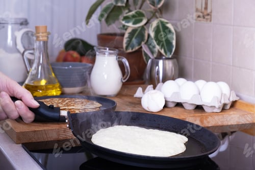 Preview: Housewife woman bakes pancakes for breakfast.