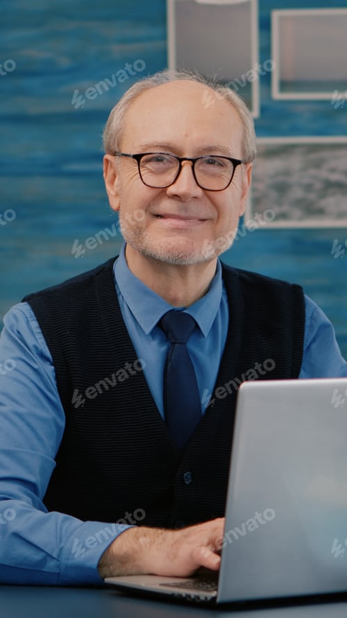 Preview: Retired manager sitting at desk in front of camera smiling