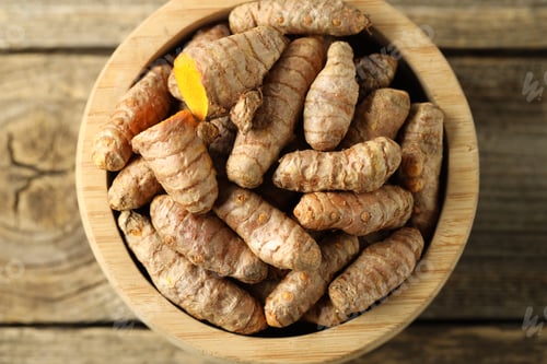 Preview: Tumeric rhizomes in bowl on wooden table, top view