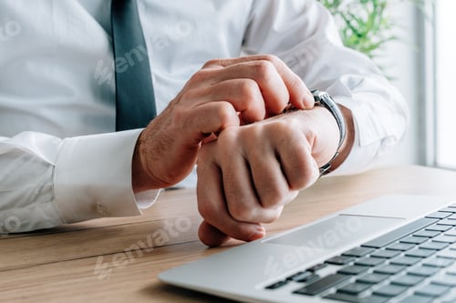 Preview: Businessman late for meeting checking time on his watch in business office