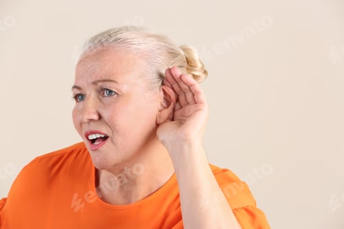 Preview: Mature woman with hearing problem on light background