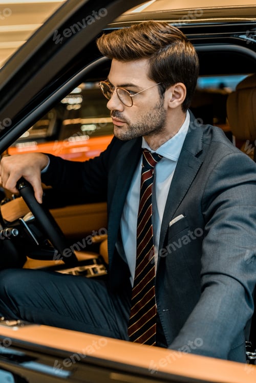 Preview: stylish young businessman closing door while sitting in automobile