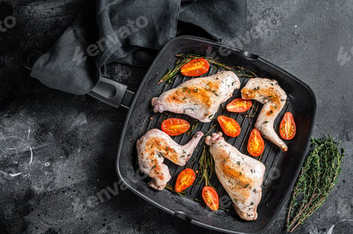 Preview: Roasted rabbit legs in a pan with thyme. Black background. Top view