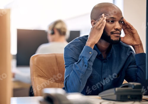 Preview: Shot of a young call centre agent looking stressed out while working on a computer in an office