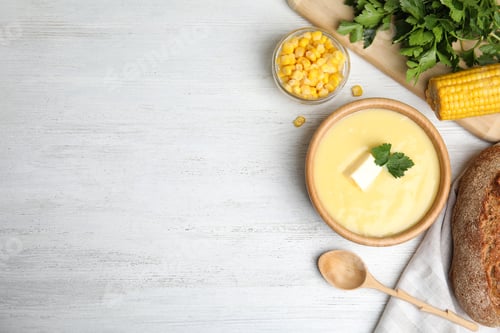 Preview: Delicious corn cream soup served on white wooden table, flat lay. Space for text