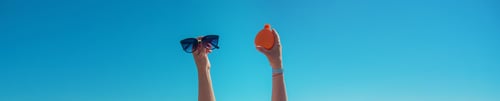 Sunglasses and Sunscreen Against a Vibrant Blue Sky
