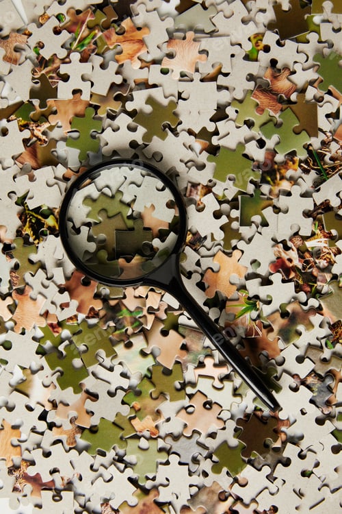 Preview: top view of magnifying glass and jigsaw puzzle pieces on grey