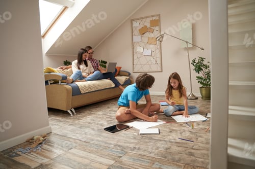 Aperçu: Happy family at home. Young mother and father relaxing on sofa and watching movie on