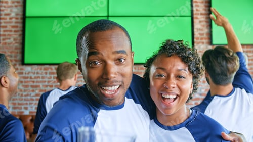 Preview: Portrait Of Couple Wearing Team Colours Watching Game In Sports Bar On Green Screen Celebrating Win