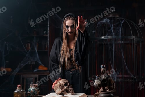 Preview: Halloween concept. Witch portrait close up with dreadlocks dressed black hood standing dark room wit