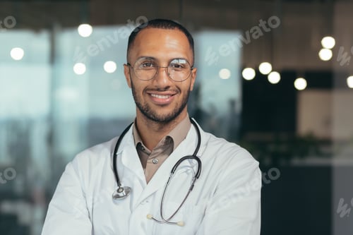 Preview: Close-up photo. Portrait of a young male hispanic doctor. Standing in a white coat and a