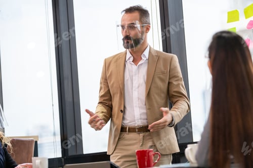 Preview: Business CEO man wearing face shield presenting company planning to the team