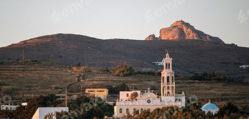 Preview: Tinos island Chora town Cyclades Greece. Sunbeam colors Panagia Megalohari Church and hill around.