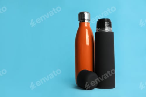 Preview: Stylish thermo bottles on light blue background, space for text