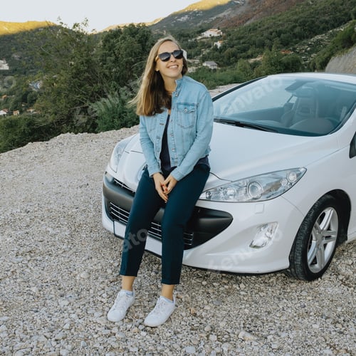 Preview: Smiling woman in sunglasses sitting near a car