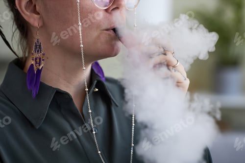 Preview: Close-up of young female smoker releasing cloud of white thick vapor