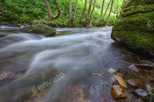 Preview: Current in a river surrounded by large mossy rocks
