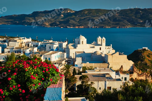 Preview: Picturesque scenic view of Greek town Plaka on Milos island over red geranium flowers