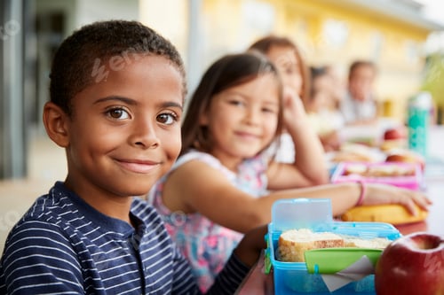 Preview: Young boy and girl at school lunch table smiling to camera