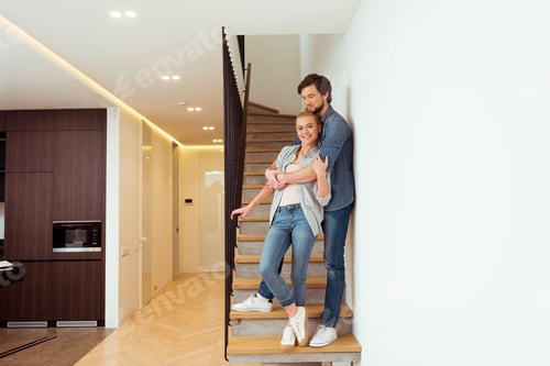 Aperçu: handsome man embracing beautiful wife on stairs at home