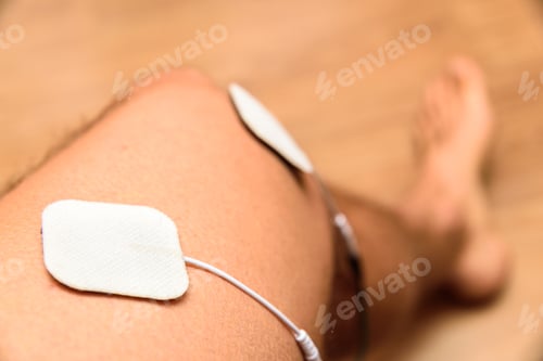 Preview: Electrodes of an electrostimulator on the leg of a male athlete.