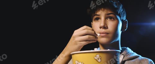 Preview: Boy eating popcorn and watching a movie at the cinema