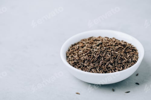 Preview: Cumin seeds or caraway in white bowl with copy space