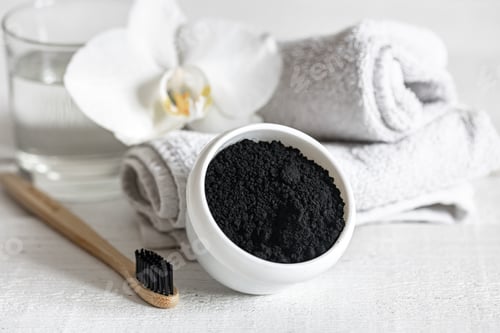 Preview: Close up of black natural teeth whitening powder and toothbrush.