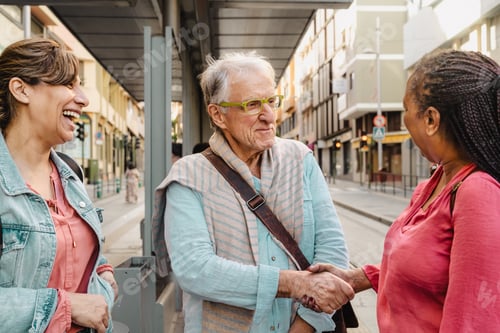 Preview: Happy multiracial people talking while waiting at the bus station in the city center