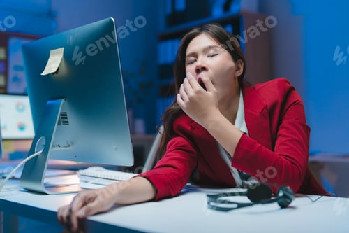 Preview: Exhausted businesswoman yawning at office desk at night