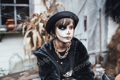 Preview: Beautiful scary little girl celebrating halloween. Terrifying black, white half-face makeup and witc