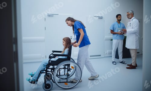Preview: Young nurse pushing little girl on wheelchair at hospital corridor.