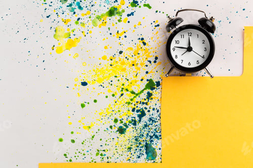Preview: Vintage alarm clock on a creative colorful background with paint sprinkles
