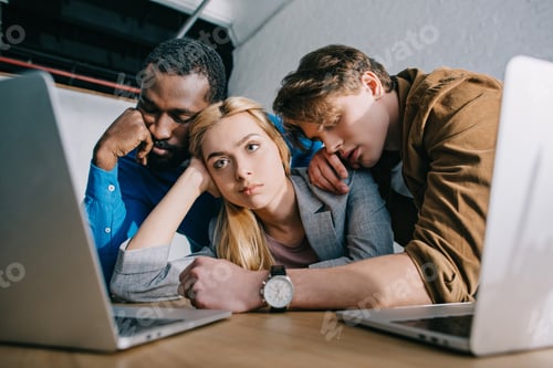 Preview: tired businesswoman with two sleeping male colleagues on shoulders sitting at table