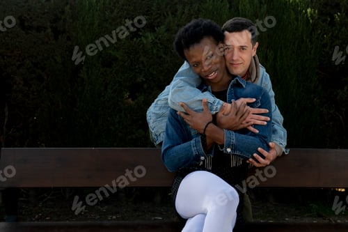 Preview: Interracial gay couple embracing on park bench, showing love and affection
