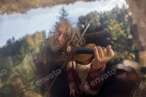 Preview: Senior man playing violin behind glass window
