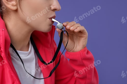 Preview: Woman blowing whistle on purple background, closeup
