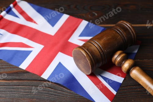Preview: Judge's gavel and flag of United Kingdom on wooden table, closeup