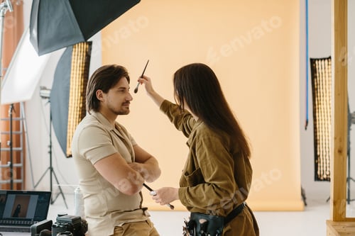 Vista previa: Maquilladora trabajando durante una sesión de fotos mientras prepara el look de la modelo