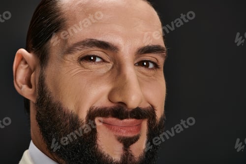 Preview: close up portrait of bearded and happy arabic man smiling while posing on black background