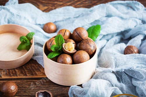 Preview: Macadamia nuts in shell with mint leaves and honey on wooden background