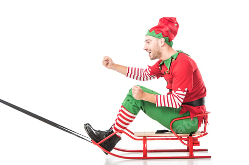 Preview: excited happy man in christmas elf costume riding sleigh isolated on white