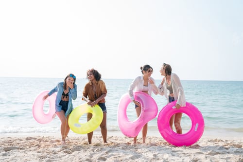 Preview: Group of teenage with floaty on the beach having fun in a sunny day.