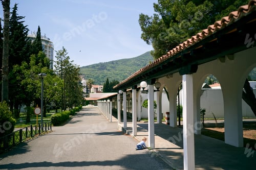 Preview: Little girl crawls along the road along the long pavilion in the park