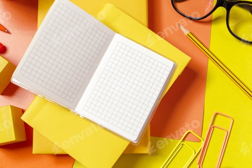 Preview: Writing tools on a desk with yellow paper and an open notebook beside a pencil
