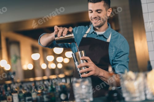 Preview: Selective Focus Of A Metal Cocktail Shaker And Smiling Bartender Pouring Liquid Into It