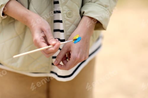 Preview: Stop War. Peace in Ukraine. woman drawing picture of flag of ukraine on hand.Antiwar support concept