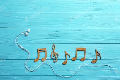 Preview: Earphones and music notes on wooden background, flat lay. Space for text