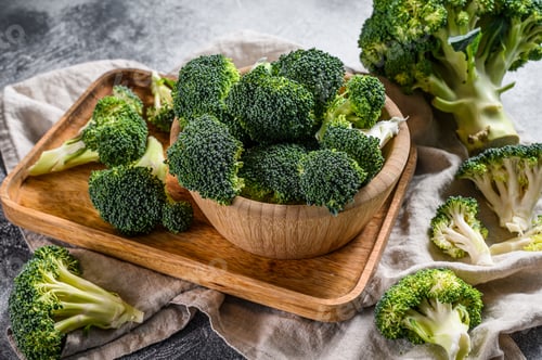 Preview: Raw broccoli in a wooden bowl. Gray background. Top view